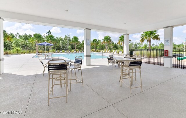 view of patio with a community pool and fence