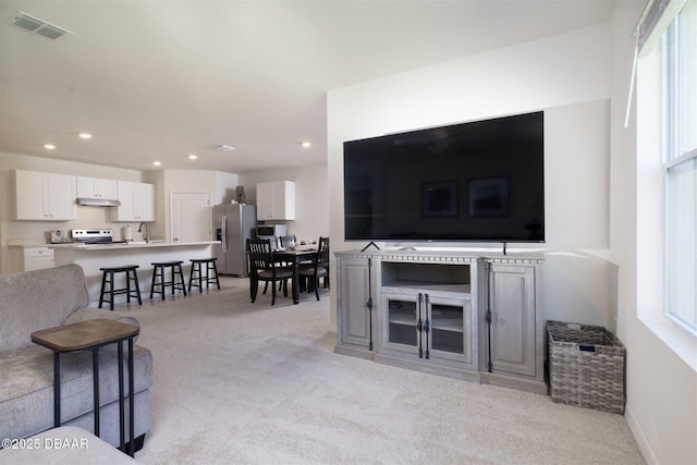 living room featuring recessed lighting, visible vents, baseboards, and light colored carpet