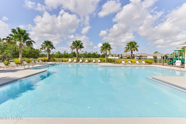 pool with a patio area, fence, and playground community