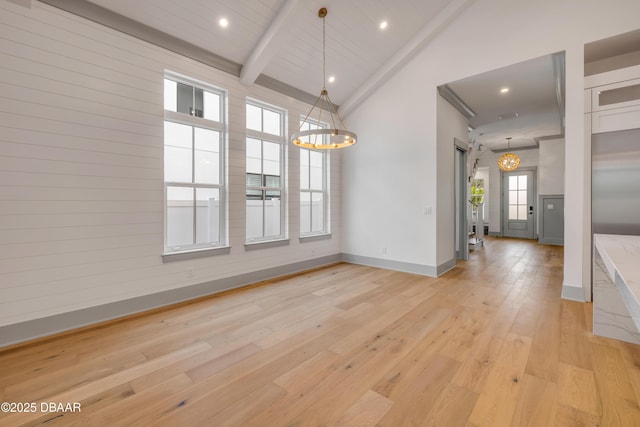 unfurnished dining area with baseboards, light wood-style floors, a chandelier, and beamed ceiling