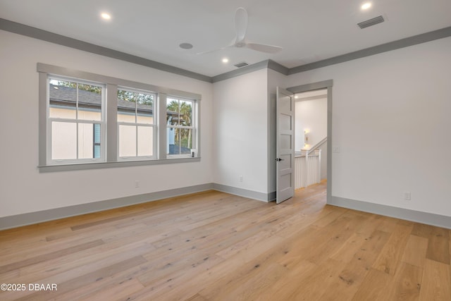 spare room featuring light wood finished floors, baseboards, visible vents, and a ceiling fan