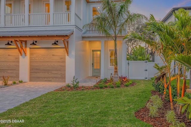 view of front of property with driveway, a gate, a balcony, a front lawn, and a garage