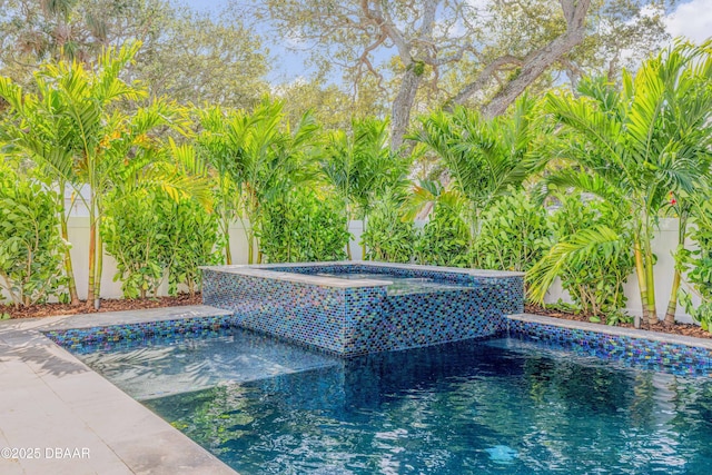 view of swimming pool featuring a pool with connected hot tub and fence