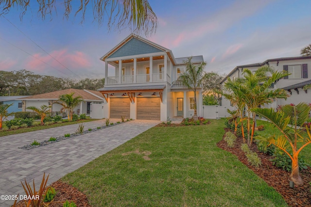 view of front of property featuring a gate, an attached garage, fence, a balcony, and decorative driveway
