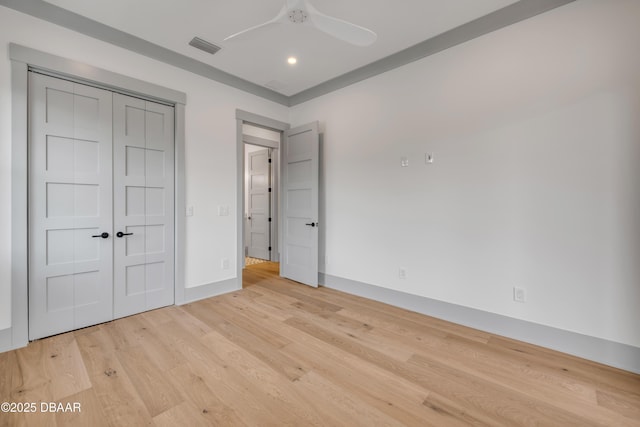 unfurnished bedroom featuring a closet, a ceiling fan, light wood finished floors, baseboards, and visible vents