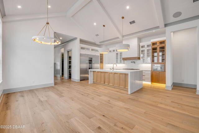 kitchen with light countertops, tasteful backsplash, beamed ceiling, light wood finished floors, and visible vents
