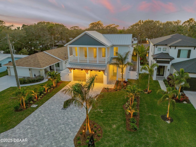 view of front facade featuring a standing seam roof, metal roof, a balcony, decorative driveway, and a yard
