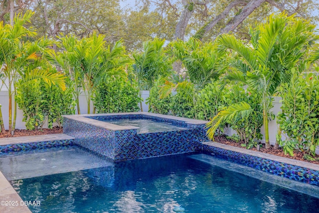 view of pool featuring an in ground hot tub and fence