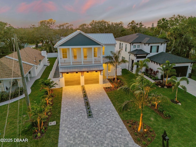 raised beach house with fence, a lawn, driveway, and a garage