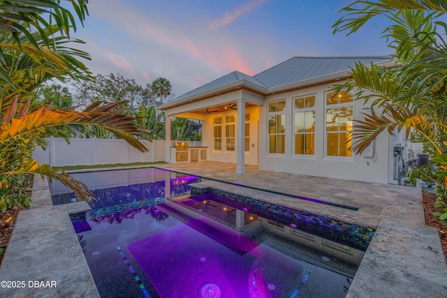 pool at dusk featuring a fenced backyard, a fenced in pool, a patio, and a ceiling fan