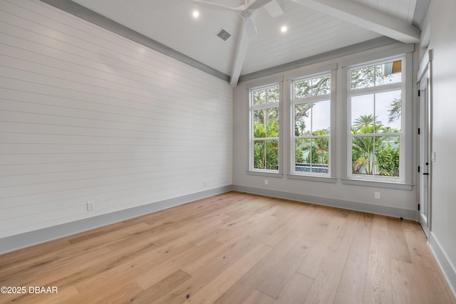 spare room with baseboards, light wood-style floors, ceiling fan, visible vents, and vaulted ceiling with beams