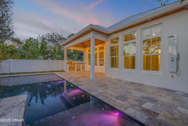 pool at dusk with fence, a fenced in pool, a ceiling fan, and a patio area