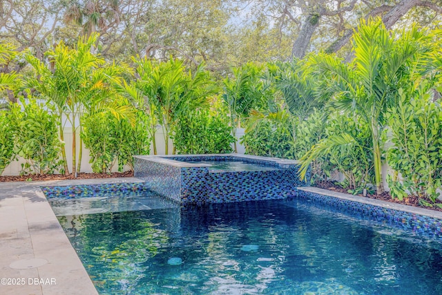 pool featuring fence and an in ground hot tub