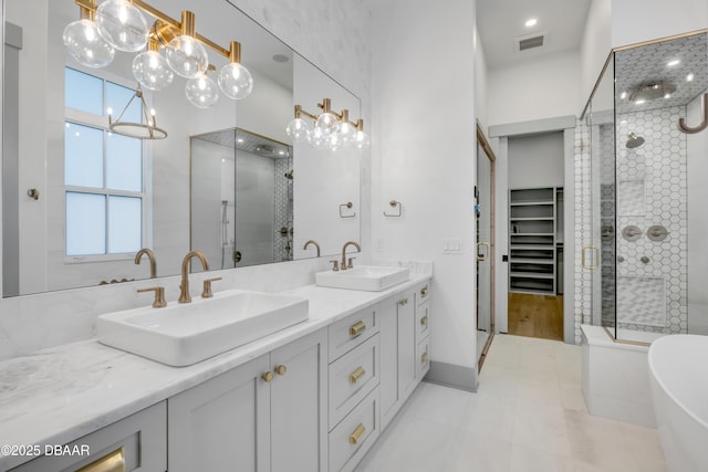 bathroom featuring a stall shower, double vanity, visible vents, and a sink