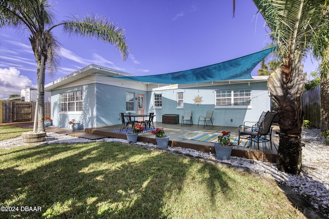 rear view of house featuring a lawn and a deck