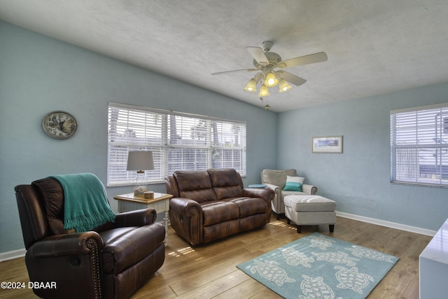 living room featuring ceiling fan, lofted ceiling, a textured ceiling, and light hardwood / wood-style floors