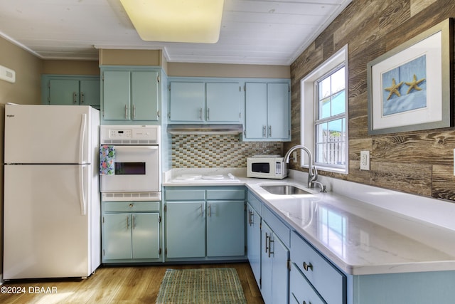 kitchen with white appliances, tasteful backsplash, sink, ornamental molding, and light stone counters