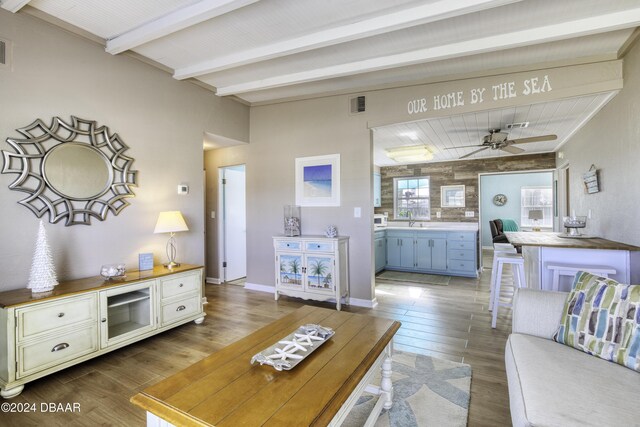 living room featuring ceiling fan, sink, and beamed ceiling