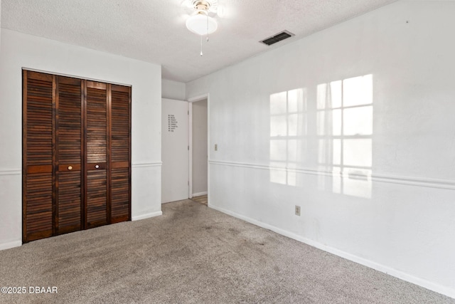 unfurnished bedroom featuring carpet flooring, a closet, and a textured ceiling