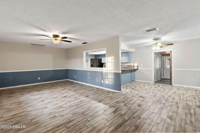 unfurnished living room with ceiling fan, wood-type flooring, and a textured ceiling