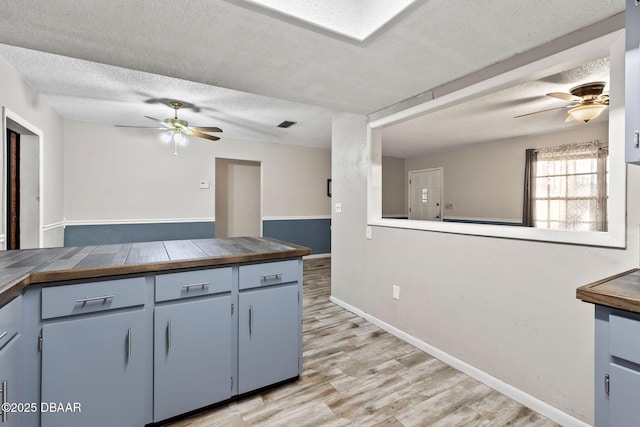 kitchen featuring a textured ceiling, tile countertops, ceiling fan, and light wood-type flooring