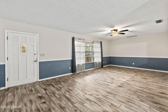 spare room featuring a textured ceiling, ceiling fan, and light wood-type flooring