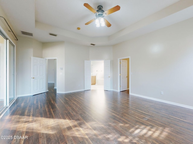 unfurnished bedroom with a tray ceiling and dark wood-type flooring