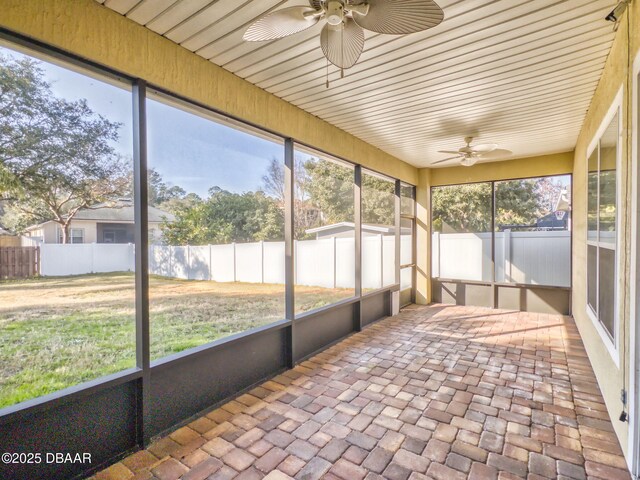 unfurnished dining area with ceiling fan with notable chandelier, a raised ceiling, and hardwood / wood-style floors