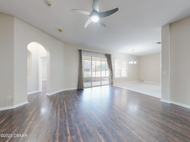 empty room featuring ceiling fan with notable chandelier and dark wood-type flooring