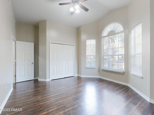 unfurnished bedroom with lofted ceiling, dark hardwood / wood-style floors, ceiling fan, and a closet