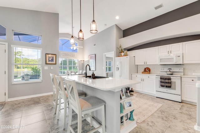 kitchen with white cabinets, white appliances, hanging light fixtures, and an island with sink