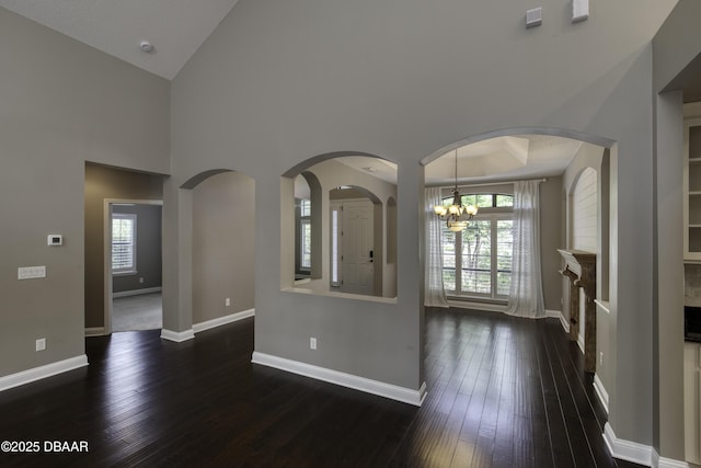 2809 Oakgrove Ave, Saint Augustine, FL 32092 - unfurnished living room with dark wood-style floors, a chandelier, high vaulted ceiling, and arched walkways