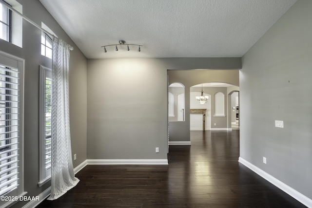 2809 Oakgrove Ave, Saint Augustine, FL 32092 - empty room featuring arched walkways, wood finished floors, a textured ceiling, and a chandelier