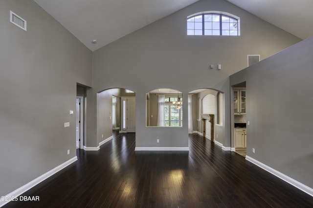2809 Oakgrove Ave, Saint Augustine, FL 32092 - unfurnished living room featuring high vaulted ceiling, dark wood-style floors, healthy amount of natural light, and arched walkways