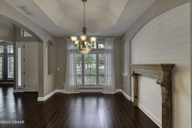 2809 Oakgrove Ave, Saint Augustine, FL 32092 - unfurnished dining area featuring a chandelier, arched walkways, dark wood-style flooring, and a tray ceiling
