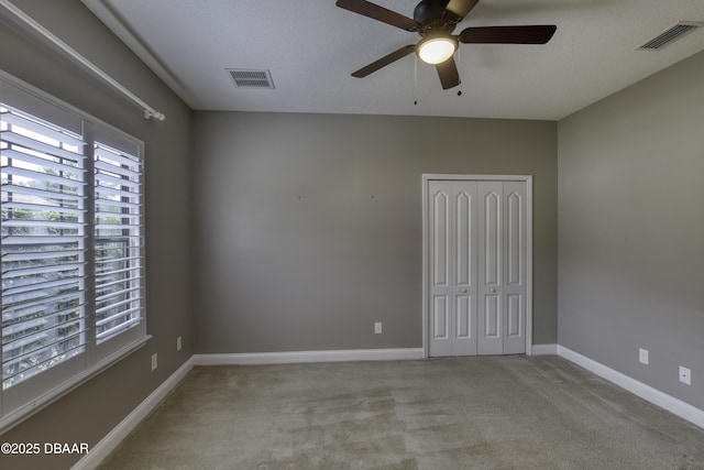 2809 Oakgrove Ave, Saint Augustine, FL 32092 - unfurnished bedroom featuring multiple windows, carpet floors, a closet, ceiling fan, and a textured ceiling