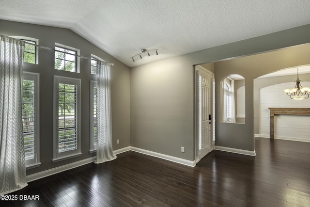 2809 Oakgrove Ave, Saint Augustine, FL 32092 - spare room featuring a chandelier, vaulted ceiling, a textured ceiling, hardwood / wood-style flooring, and arched walkways