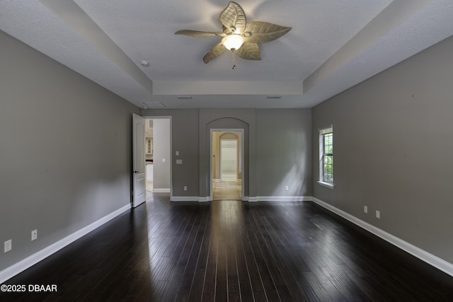 2809 Oakgrove Ave, Saint Augustine, FL 32092 - empty room featuring a raised ceiling, a ceiling fan, dark wood finished floors, and arched walkways