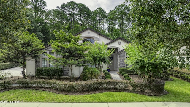 2809 Oakgrove Ave, Saint Augustine, FL 32092 - view of property hidden behind natural elements with stone siding, stucco siding, a front lawn, and driveway