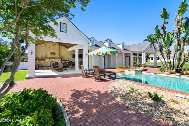 view of swimming pool featuring a patio and an outdoor stone fireplace