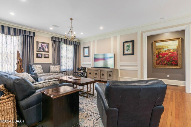 living room featuring a notable chandelier, light hardwood / wood-style floors, and crown molding