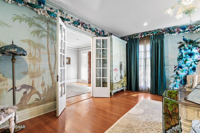 entryway with hardwood / wood-style floors, ornamental molding, and french doors