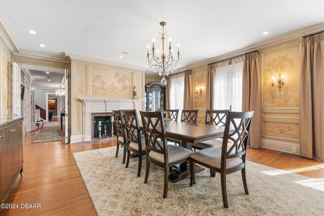 dining area featuring a brick fireplace, an inviting chandelier, crown molding, and light hardwood / wood-style flooring