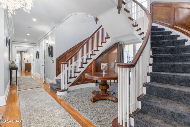 staircase featuring ornamental molding, hardwood / wood-style floors, and an inviting chandelier