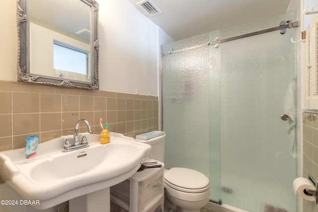 bathroom featuring sink, backsplash, an enclosed shower, toilet, and tile walls