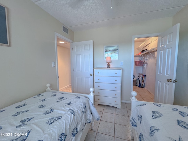 bedroom with light tile patterned floors, a textured ceiling, a closet, and a spacious closet