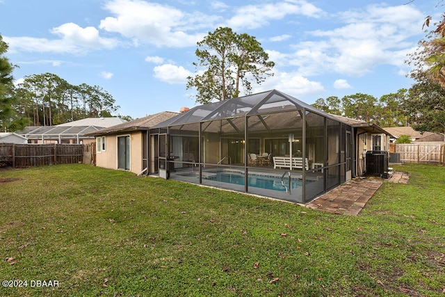 rear view of house featuring a fenced in pool, glass enclosure, and a yard