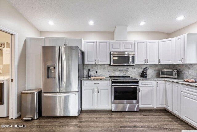 kitchen with stone countertops, appliances with stainless steel finishes, backsplash, white cabinets, and dark wood-type flooring