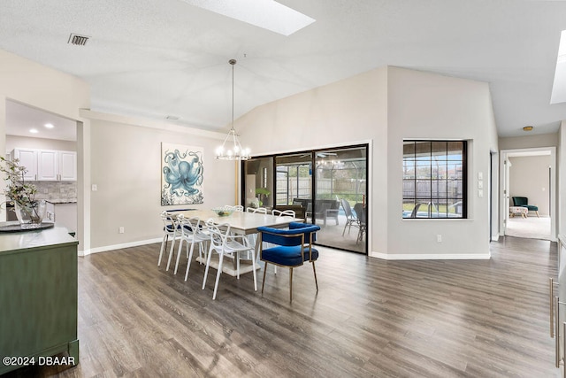 dining space with lofted ceiling with skylight, an inviting chandelier, dark hardwood / wood-style floors, and a textured ceiling