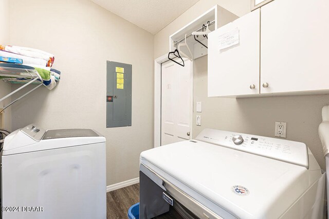 washroom featuring electric panel, separate washer and dryer, dark wood-type flooring, and cabinets